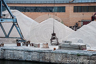 Port work: loading and unloading large piles of sand Stock Photo