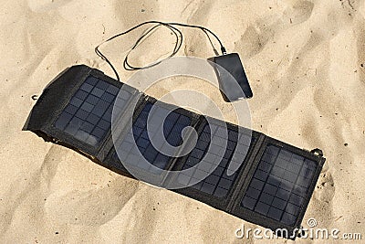 Portable solar panel is on the beach charges mobile phone. Stock Photo