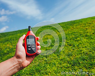 Portable thermometer in hand measuring outdoor air temperature and humidity Stock Photo
