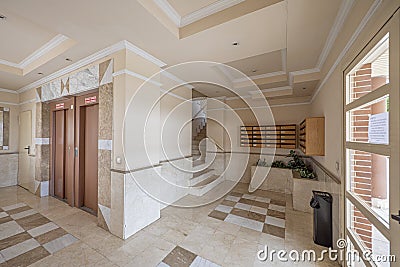 Portal of a building with light colored marble tiles and twin elevators Stock Photo