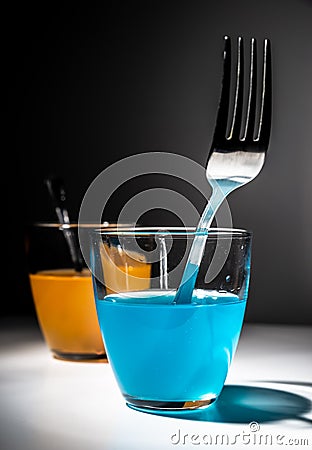 Portal concept made of glasses and fork coming out of blue liquid. Teleportation concept with fork coming in to orange liquid and Stock Photo