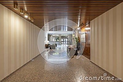 Portal of a residential house with stairs and granite floors, papered walls and an elevator with a brown metal door and a lounge Stock Photo