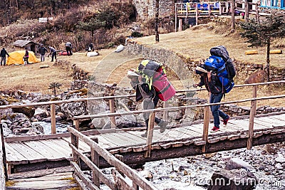 Porters of Himalaya Mountain expedition crossing wooden bridge Editorial Stock Photo