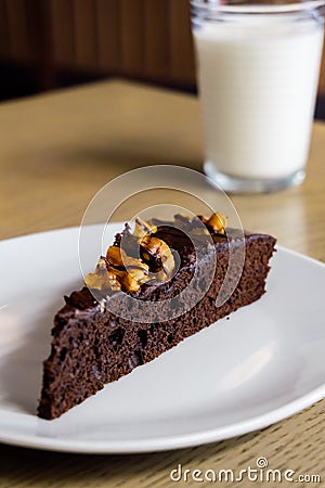 Portion of brownie cake with walnuts, glass of milk in the background Stock Photo