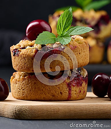 Portion crumble pie with cherries on a wooden board decorated with green mint leaves Stock Photo