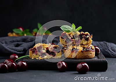 Portion crumble pie with cherries on a wooden board decorated with green mint leaves Stock Photo