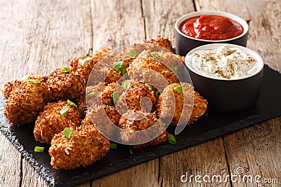 Portion Deep-fried chicken nuggets in coconut flakes served with ketchup and mayonnaise close-up on a slate board. horizontal Stock Photo