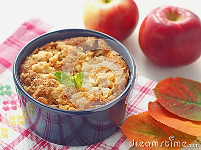 Portion of fresh coffeecake in a mug. Fresh pudding decorated with autumn leaves and red apples. Stock Photo
