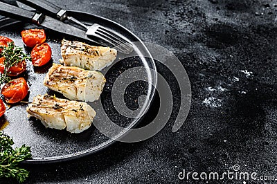 A portion of Grilled, baked pollock or coalfish fillets. Black background. Top view. Copy space Stock Photo