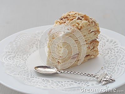 Portion of multi layered cake, cut off with funny spoon. Puff pastry cake decorated with crumbs Stock Photo