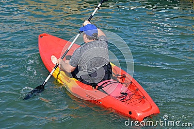 Portly Gentleman Paddling a Bright Orange Kayak Editorial Stock Photo