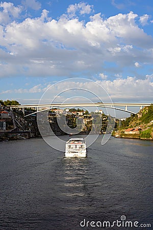 A river, a bridge, roofs of houses and a large white pleasure cruise boat in the light of the setting sun Editorial Stock Photo