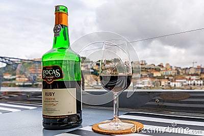 Glass and bottle of port wine with blurred cityscape of Porto Portugal in the background Editorial Stock Photo