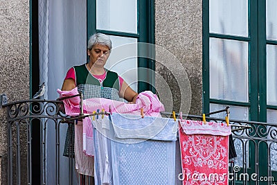 Porto, Portugal - October 06, 2018: Unidentified women dry linen on the balcony of traditional house in Porto Editorial Stock Photo