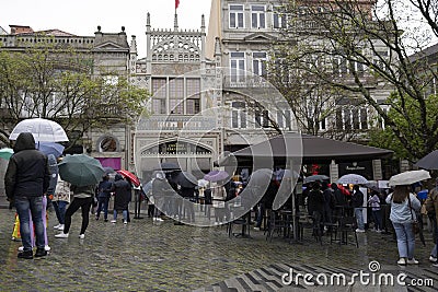 Rainy day in the city of Porto, with a huge queue of tourists to enter the Lello bookstore 