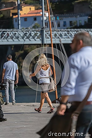 View people on the docks of Ribeira, senior woman walking in focus, people bridge and river as background Editorial Stock Photo