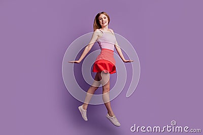 Portrait of active energetic pretty shy lady jump go wear pink top red mini skirt sneakers on purple background Stock Photo