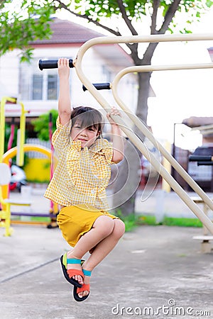 Portrait active girl plays in the hanging bar. Children are exercising. Child play in the playground. Stock Photo