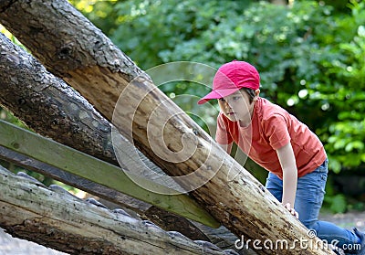 Portrait active kid climbing up into a treehouse in foest park, Child boy having sun playing in the playground on summer. Summer Stock Photo