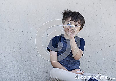 Portrait active little boy playing with toy airplane against gray concrete background, Child throwing foam airplane, Kid playing Stock Photo