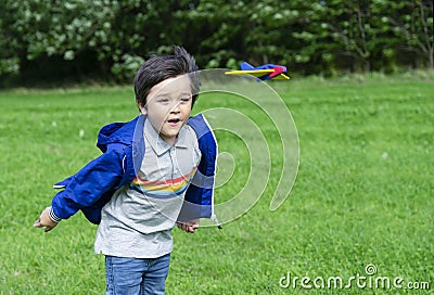 Portrait active little boy playing with toy airplane against green nature background, Child throwing foam airplane, Kid playing in Stock Photo