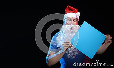 Portrait actor male in cap and beard of Santa Claus with a sheet of paper for notes in the hands Stock Photo