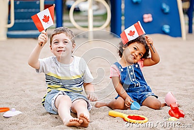 Caucasian boy and latin hispanic baby girl holding waving Canadian flags. Stock Photo