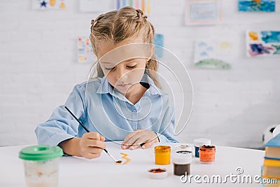 portrait of adorable focused child drawing picture with paints and brush Stock Photo