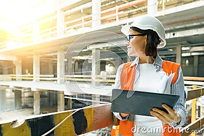 Portrait of adult female builder, engineer, architect, inspector, manager at construction site. Woman with plan, digital tablet Stock Photo