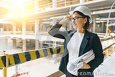 Portrait of adult female builder, engineer, architect, inspector, manager at construction site. Woman with plan, looking at Stock Photo