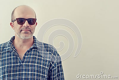 Portrait of an adult man with a gray beard with dark glasses shirt on a light background, toned. Stock Photo