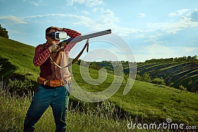 Portrait with adult man wearing VR glasses standing over landscapes background. Online hunting. Concept of virtual Stock Photo