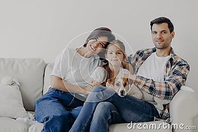 Portrait of affectionate family cuddle and sit together at couch in living room, change their home, have happy expressions. Father Stock Photo