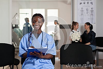 Portrait of african american assistant looking into camera while writing healthcare support service document Stock Photo