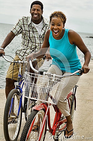 Portrait of african american couple riding bicycle on seashore Stock Photo