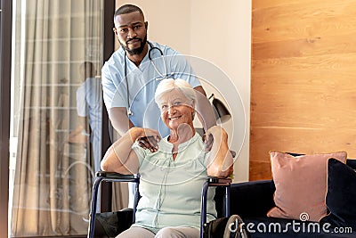 Portrait of african american male health worker and caucasian senior woman on wheelchair at home Stock Photo