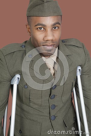 Portrait of an African American US military officer with crutches over brown background Stock Photo