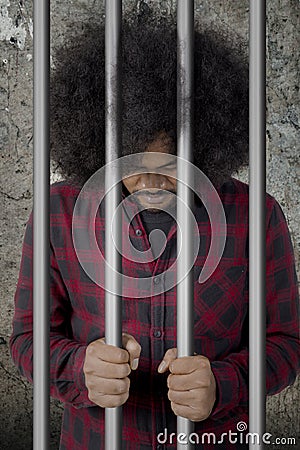 Afro man looks desperate in the jail Stock Photo