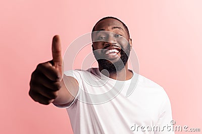 Portrait of afroamerican handsome bearded man showing thumb up sign on pink background Stock Photo