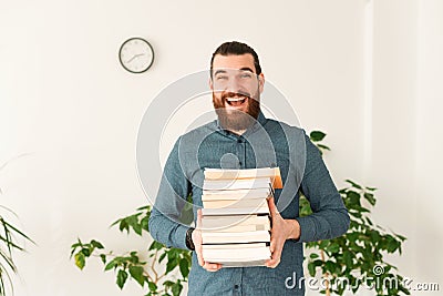 Portrait of amazed office worker man holding a bunch of books Stock Photo