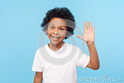 Portrait of amazing friendly little boy grinning happily and waving hi, gesturing hello with raised arm, welcoming greeting Stock Photo