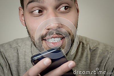 Portrait of an amused young man who is recording an audio message on his smartphone Stock Photo