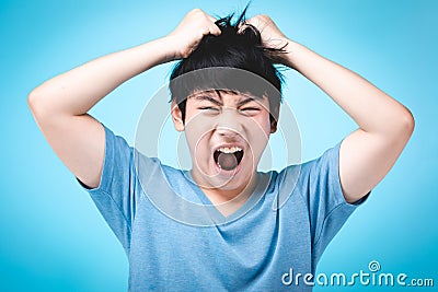 Portrait of angry asian kid on blue background Stock Photo