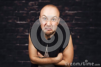 Portrait of angry bald man aggressive thug threatens. Concept portrait of a dangerous criminal on a dark street in the gateway Stock Photo