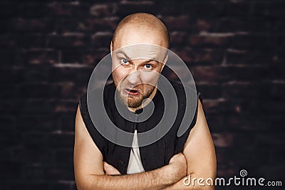 Portrait of angry bald man aggressive thug threatens. Concept portrait of a dangerous criminal on a dark street in the gateway Stock Photo