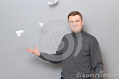 Portrait of angry mature man throwing up crumpled pieces of torn paper Stock Photo