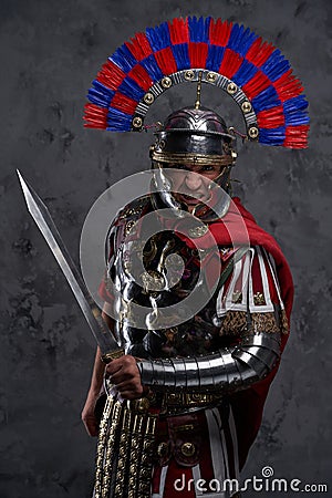 Violent legionnaire wielding gladius screaming against dark background Stock Photo