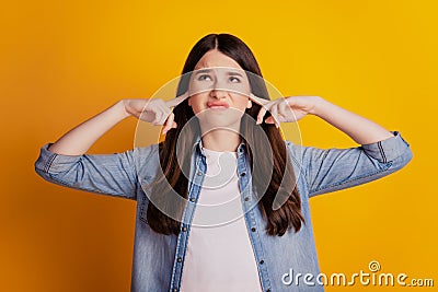 Portrait of annoyed woman fingers close ears look empty space on yellow background Stock Photo