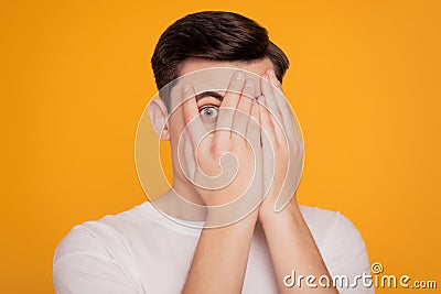 Portrait of anonymous guy hands cover face peek peering eyes on yellow background Stock Photo