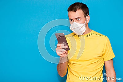 Portrait anxious young man in medical mask against virus looking at phone seeing bad news or photos with disgusting emotion on Stock Photo